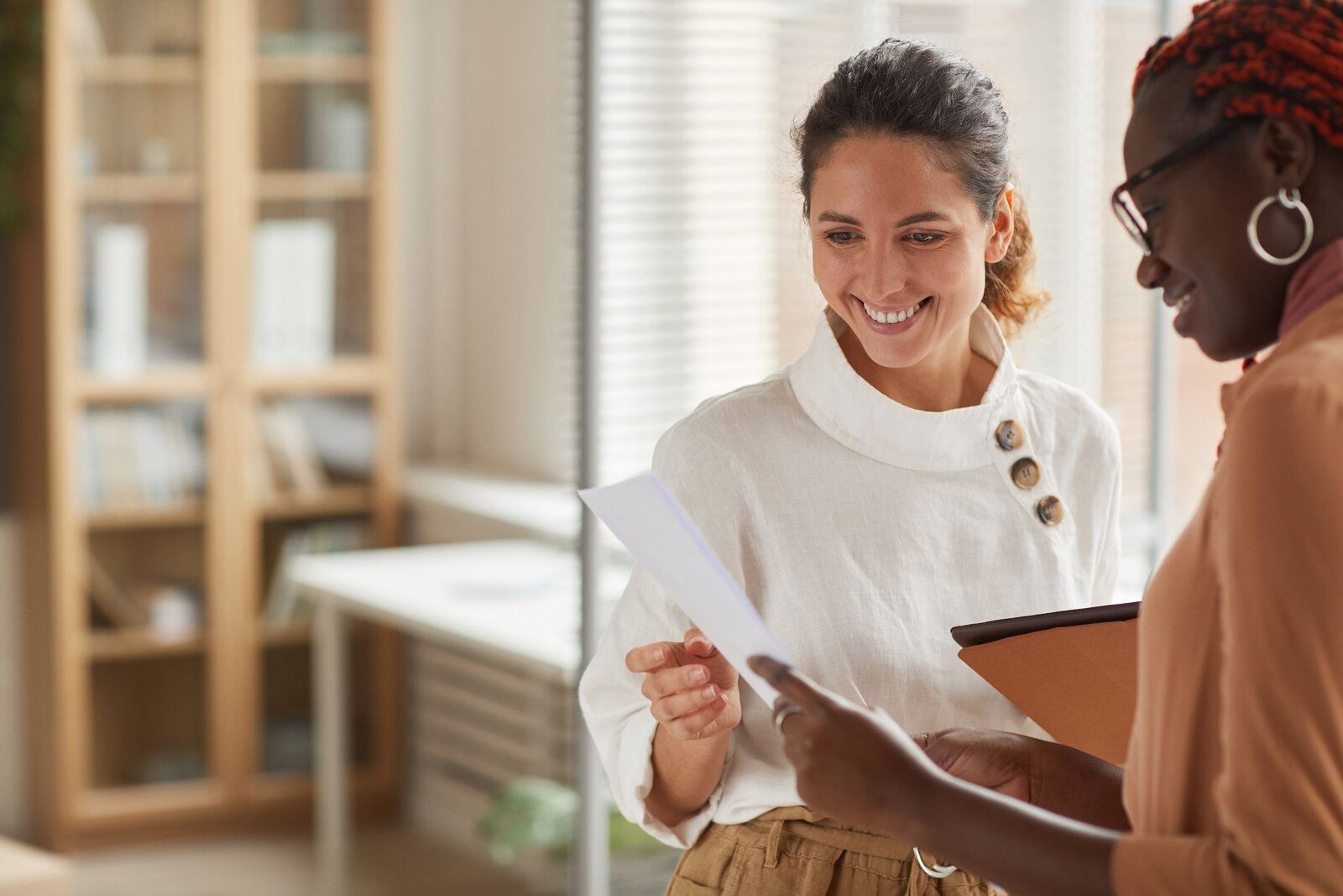 Two colleagues smiling while reviewing a document